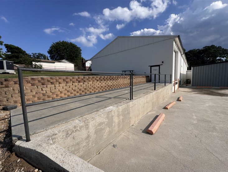 The same commercial loading dock and retaining wall after pressure washing, the concrete and block wall evenly clean