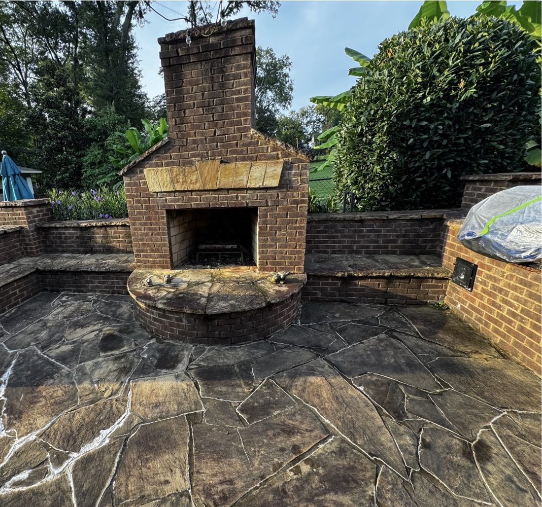 Flagstone patio and brick outdoor fireplace darkened by years of algae and organic staining, near Marietta Square, before pressure washing