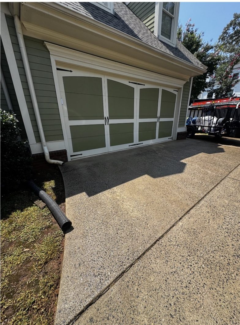 The same garage apron after surface cleaning, the concrete an even light gray with the algae gone